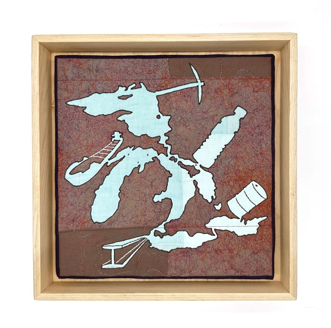 appliqued and quilted depiction of the great lakes as seen from above, merged with images of a minig pick, boat, water bottle, steel beam, and a gas barrel.