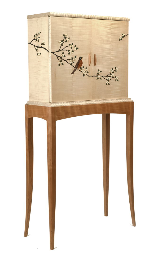 Curly maple marquetry cabinet on a cherry stand featuring cherry blossoms and a robin across the sides and doors. The veneer marquetry is all cut  shaded and assembled by hand. The interior features an adjustable cherry shelf.