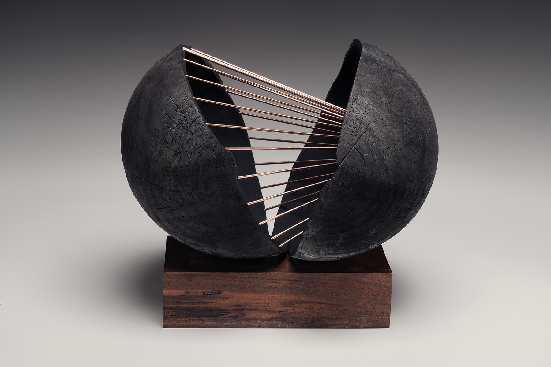 wood orb sculpture two halves joined by metal wires