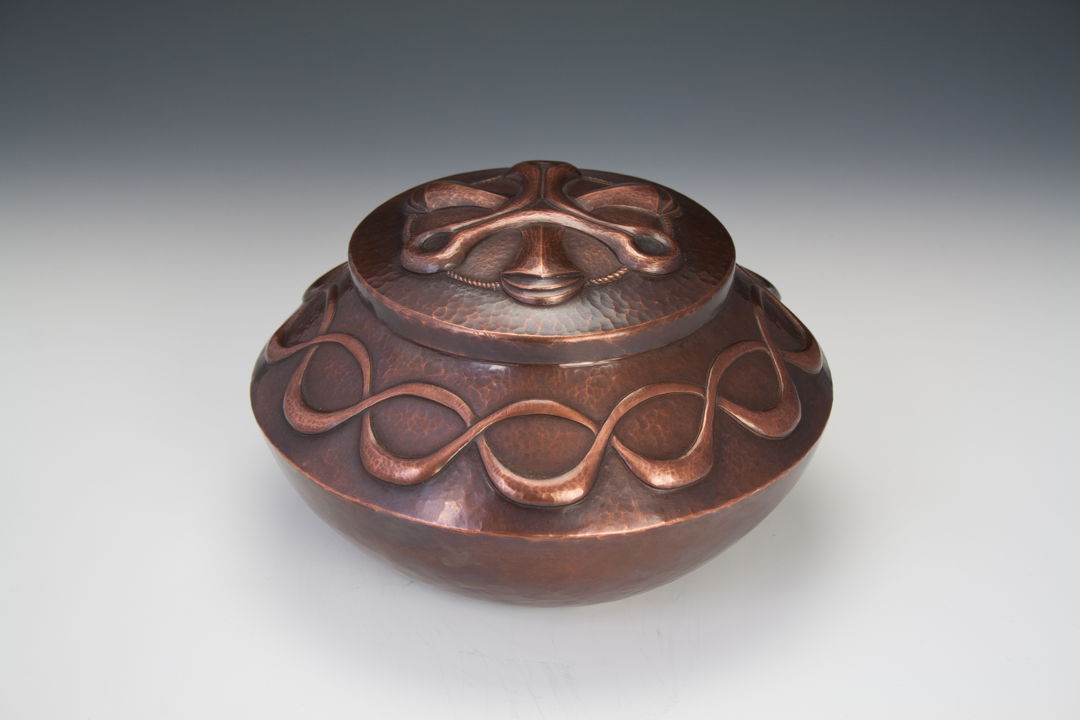 This hand raised copper vessel has features a chased lid and a rich brown patina.