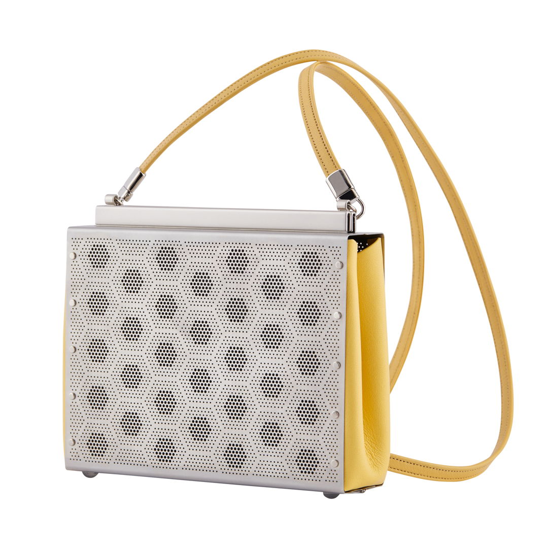 The paris purse is hand fabricated in etched stainless steel with leather gussets  a detachable strap and a magnetic closure.
