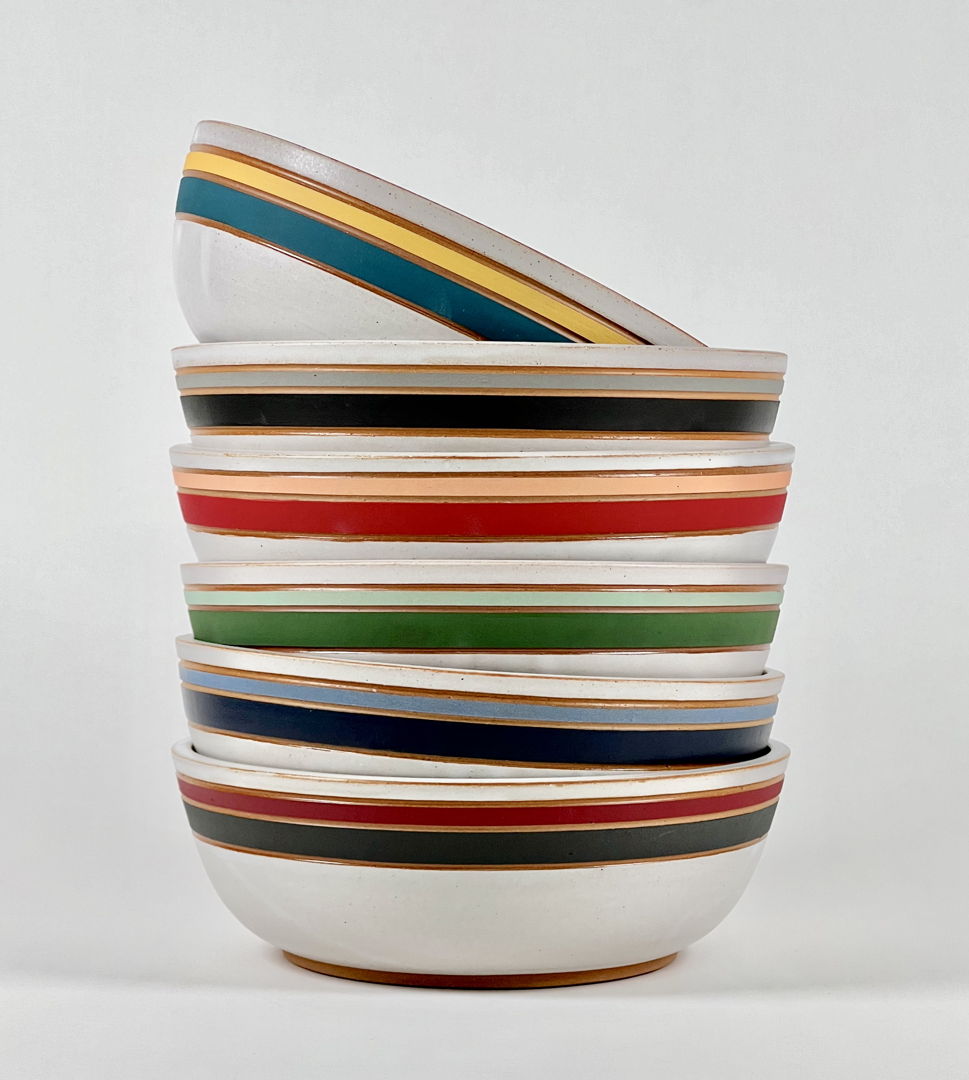 Wheel-thrown stoneware dinner bowls with satin white glaze and colorful carved underglaze stripes.