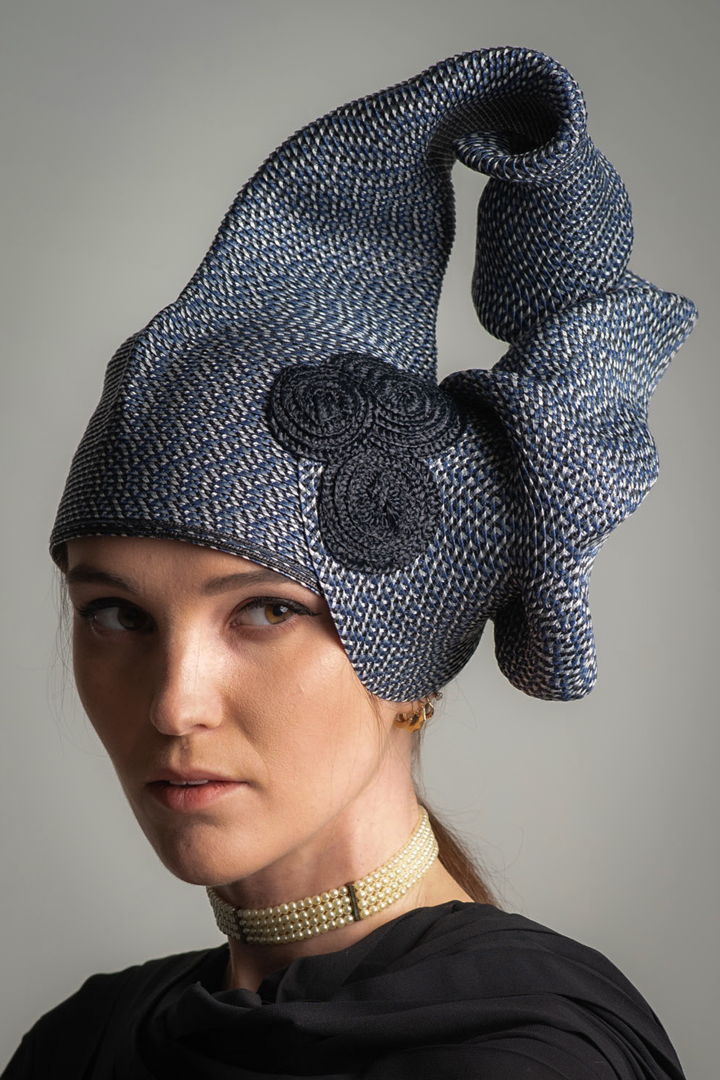 This hat I stitched from one strand of 5 mm wide Swiss braid called Rio. It is a 6 color subtle tweed. Using my hands to shape  I stitched starting as flared tube  then narrowed the tube for many inches until flared back into crown shape. The accent is Swiss Raffia circles.