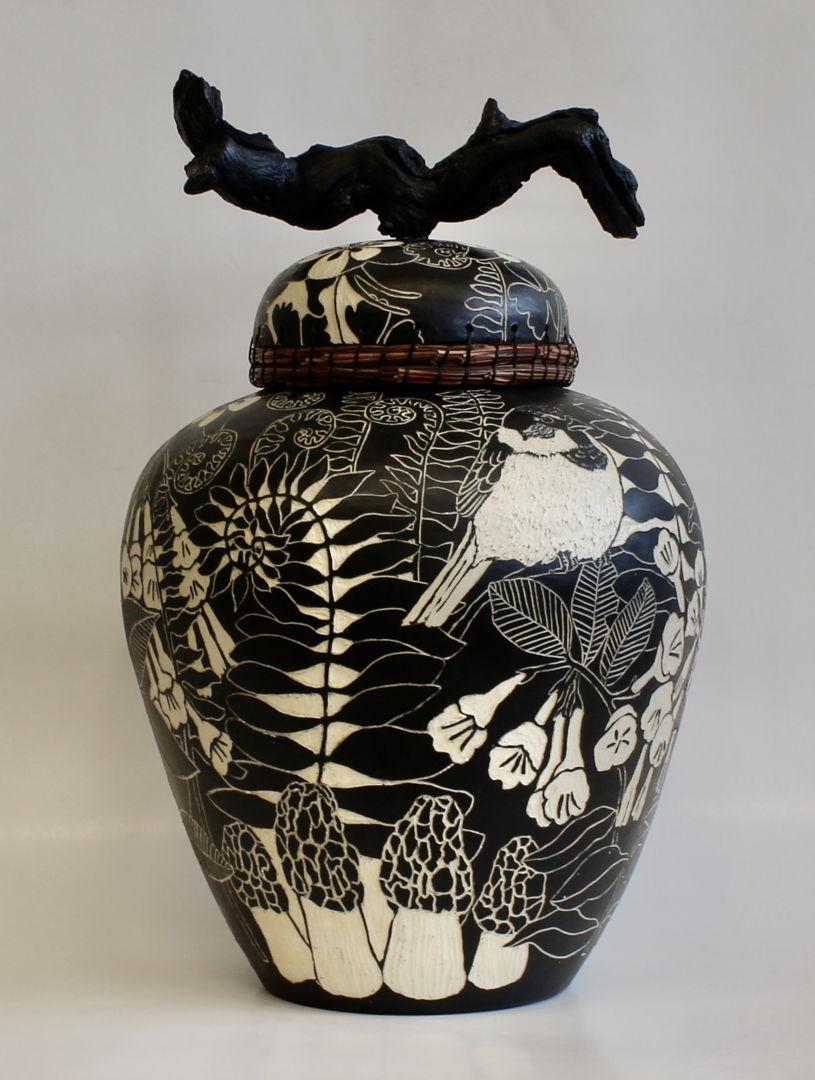 The lid of the jar is edged with woven pine needles and has a stained grapevine wood handle. The images on the surface of the pot were created using sgraffito and depict flowers  insects  birds  mushrooms and ferns.