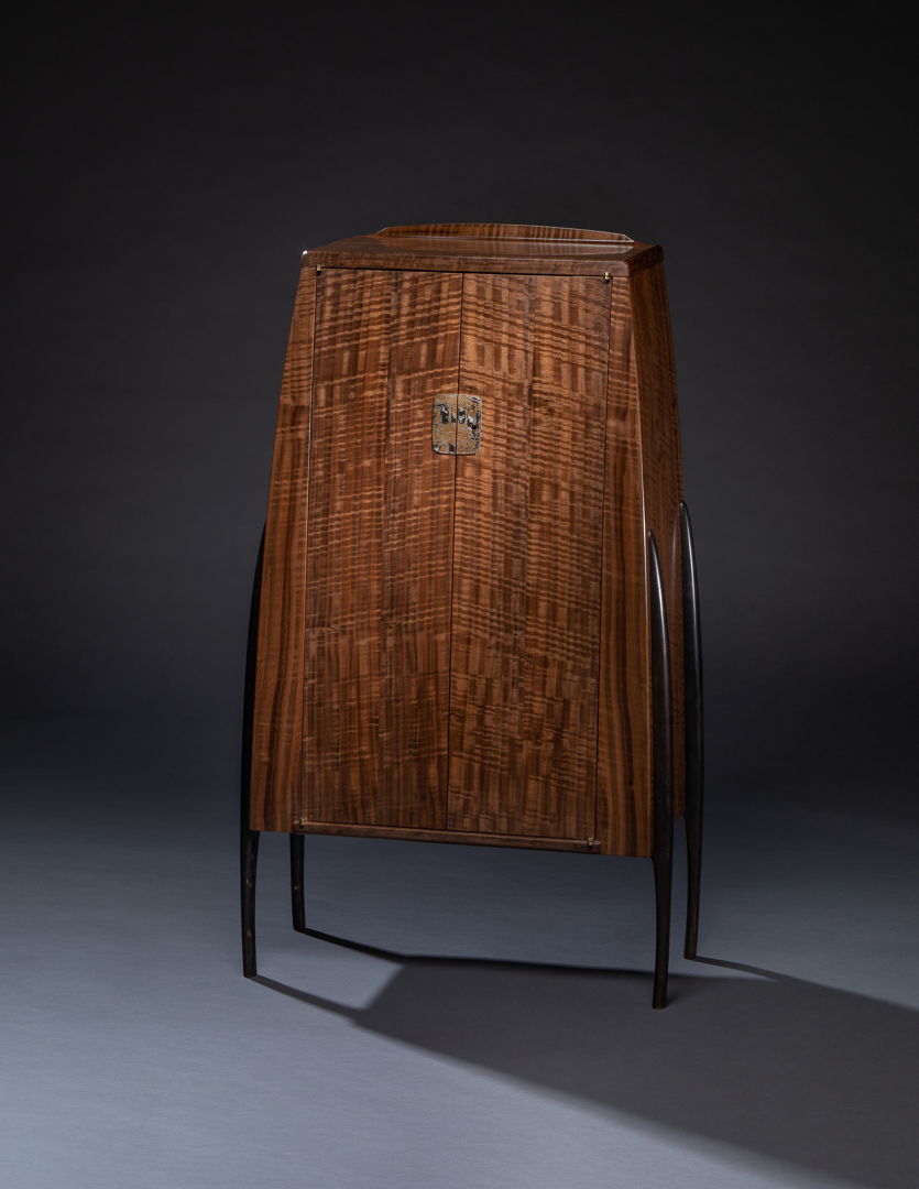 A cabinet in Claro walnut standing on cast bronze legs.This is my third piece from a heavily figured Claro walnut plank  all using shop-made Mokume-gane hardware to complement and echo the figure in the wood. Cast bronze legs lend visually slim yet solid support to the cabinet.