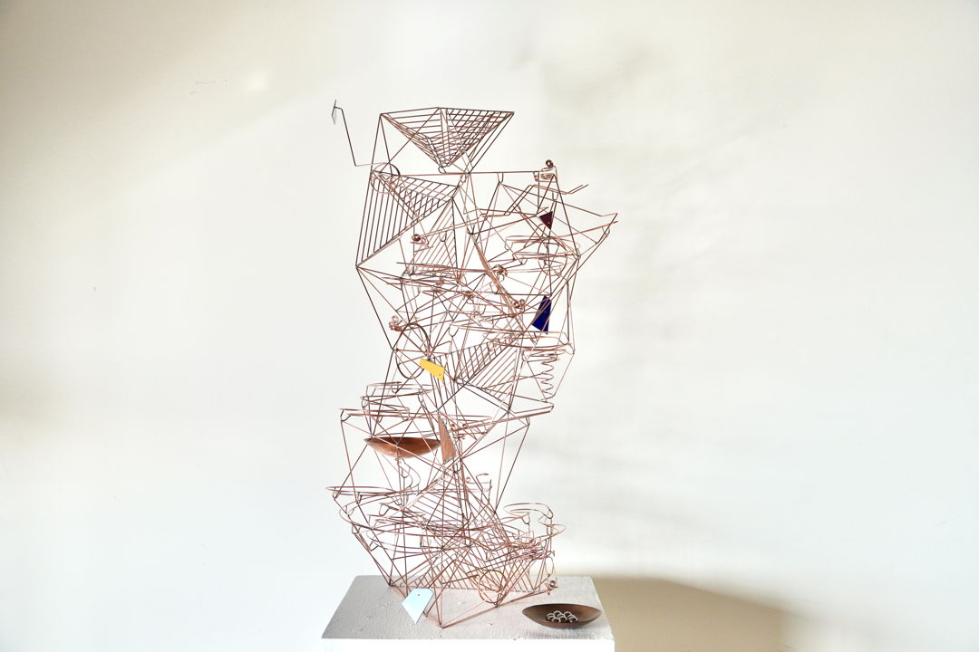 freestanding copper wire kinetic sculpture. Steel marbles can be dropped into the top of the sculpture to see them race down the sculpture on two separate tracks interacting with five moving elements with enamel counterweights.