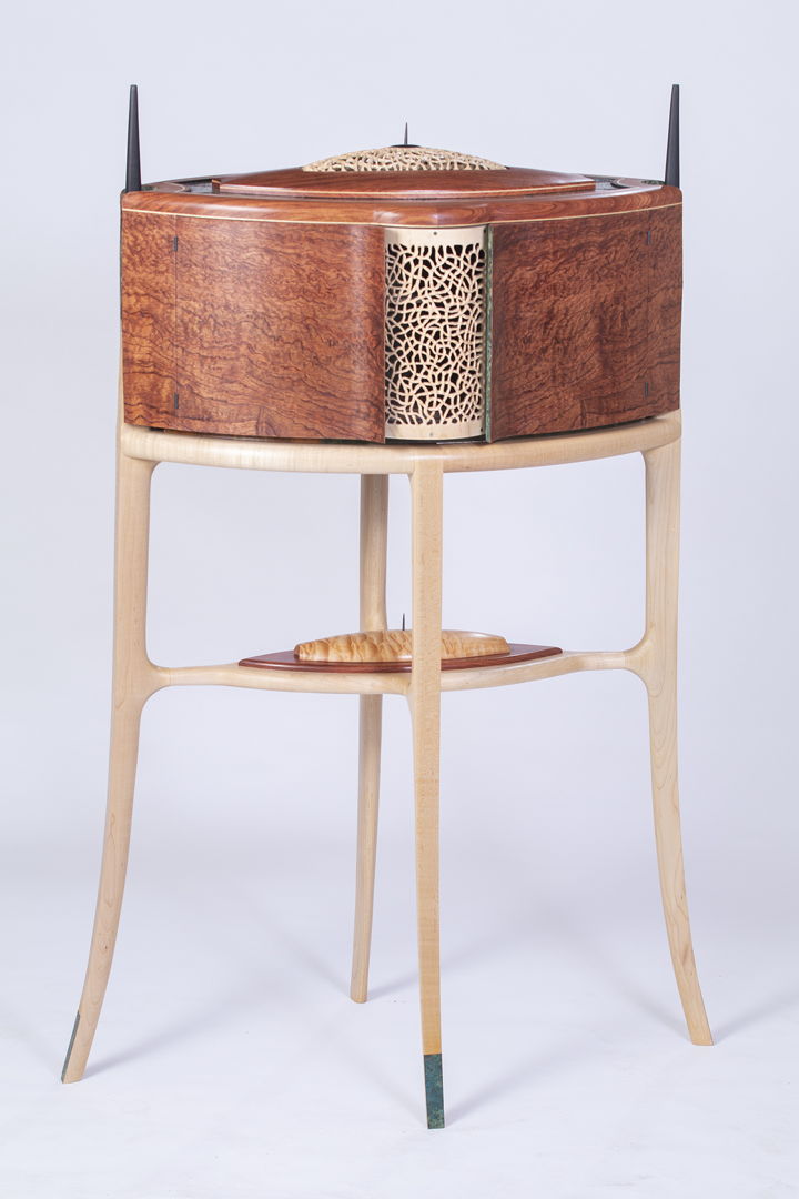 This delicate walk-about tea cabinet has matching recurved doors that provide a peek at what lies within. The rear of the cabinet is identical to the front. The piece features waterfall bubinga burl  carved and sculpted maple  an interior carousel revealing sterling silver  mother of pearl and micro-mosaic detail  and 10 drawers featuring floral inlays using mother of pearl and turquoise.