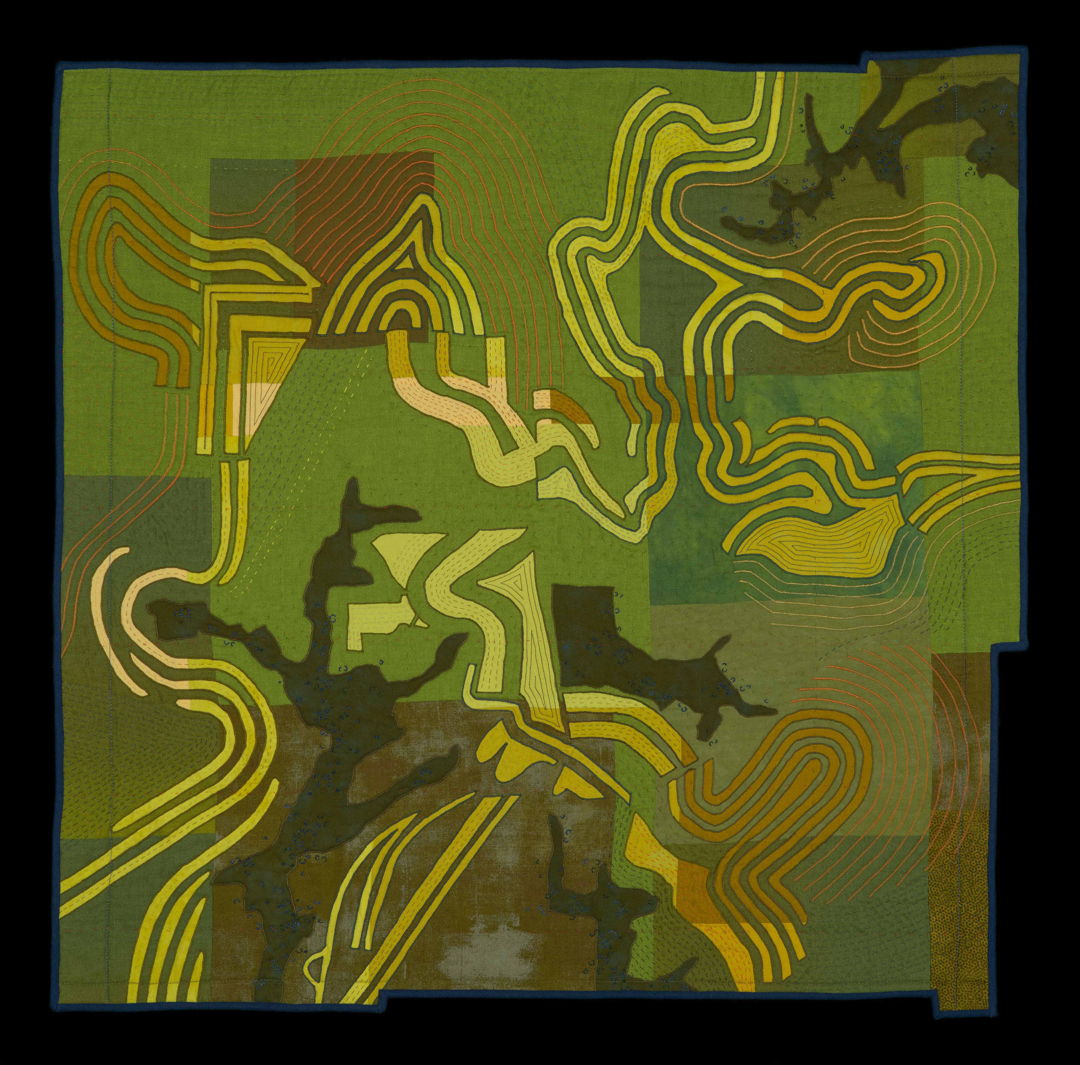 Appliqued a quilted wall hanging depicting an aerial view of a landscape. Primarily in greens, browns, and yellows.