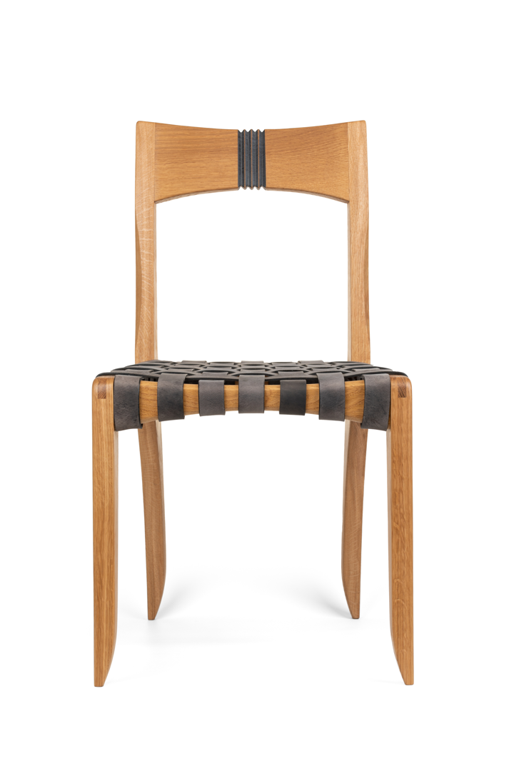 White oak dining chair with bridle joints on front legs. Back has a bandsaw carved detail that has been accented with gray paint. Seat woven with gray leather straps for a comfy sit.