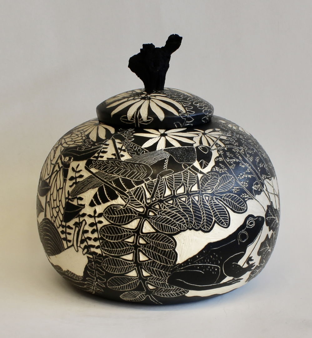 The fitted lid of this jar has a stained grapevine wood handle. The images on the surface of the pot were created using sgraffito and depict flowers  insects  birds and a frog.