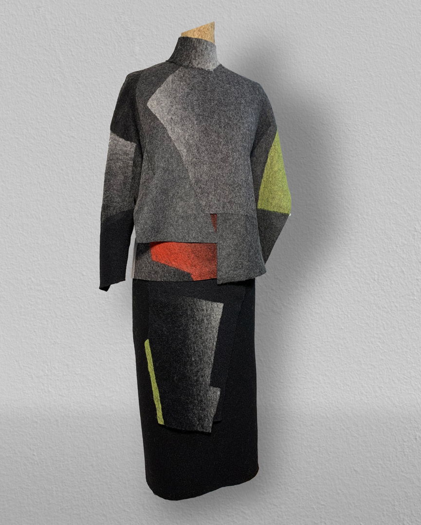 The process involved in making this ensemble begins with knitting and dying the fabric . Afterwards the pieces of fabric are cut to different shapes. The key to the work resides in felting ; the different cuts of fabric are refelted together creating a gradation of grays  black and green .