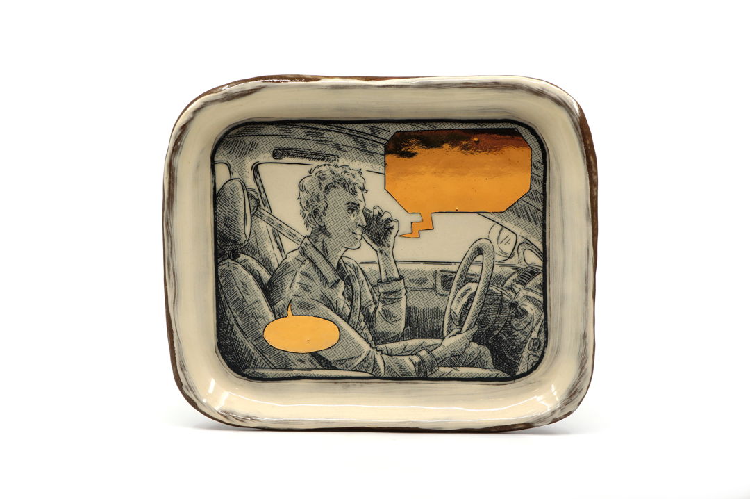 cermic tray with illustration of a man driving and speaking on the phone. The speech bubbles are empty and blocked out with gold.