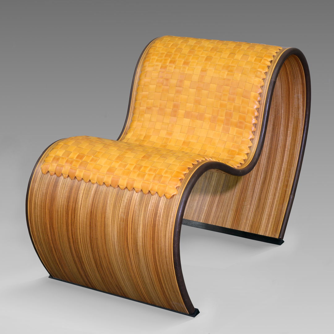 This 3-bend curved chair was custom-bent to my specs on an 8-layer plywood including the outside zebrawood veneer. The cushion was handwoven from individually hand-cut  edge-thinned and edge-dyed bridle leather strips to create a tight weave and a smooth feel.