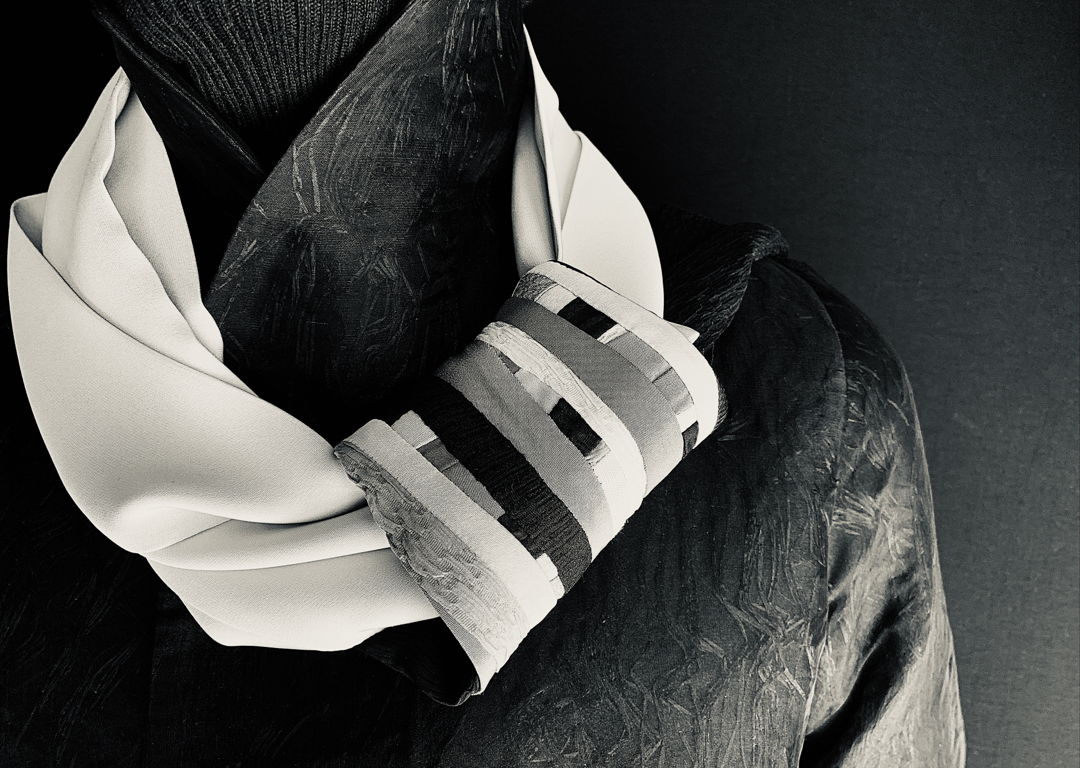 Silk scarf with attached holder made of silk pieces sewn and collagen creating surface design and functional detail that ends of scarf slide through. (Shown over our angle pointed silk reversible jacket)