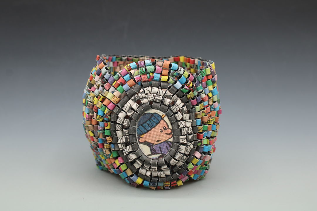 Bracelet consisting of recycled newspaper colorful comic strips and recycled newspaper black and white comic strips which are hand-formed into beads and stitched together on elastic cord.