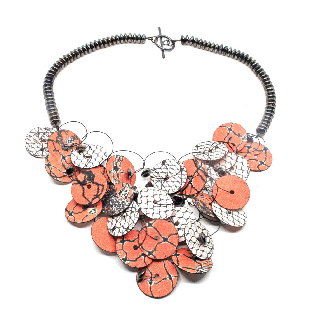 A necklace made of washable paper (cellulose + synthetic latex) printed on an etching press with soy-based archival inks. The paper petals are lashed together with ceramic beads and stainless steel cables. This piece has a hand fabricated sterling silver toggle clasp.