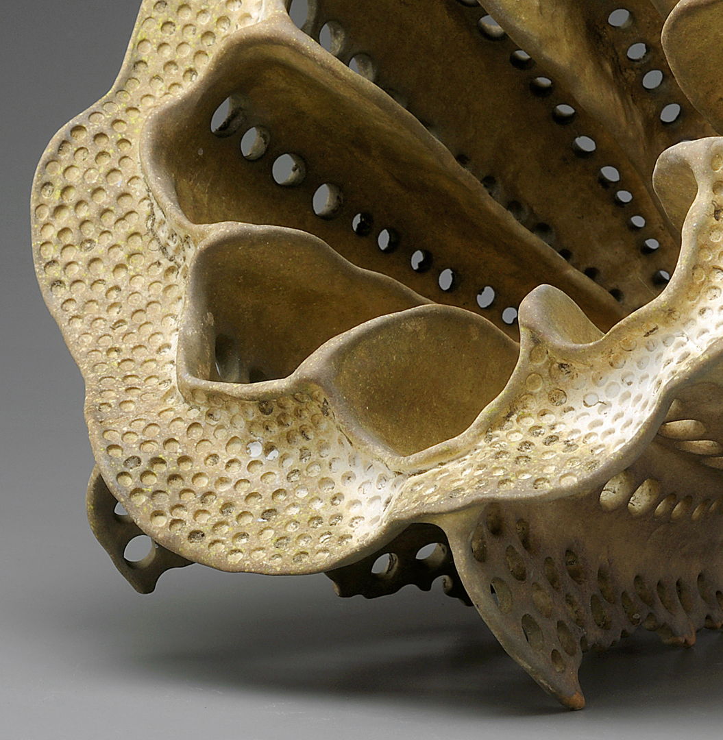 detail of an organic hollow porcelain form with grimy surface accenting the many circular indents covering the piece.