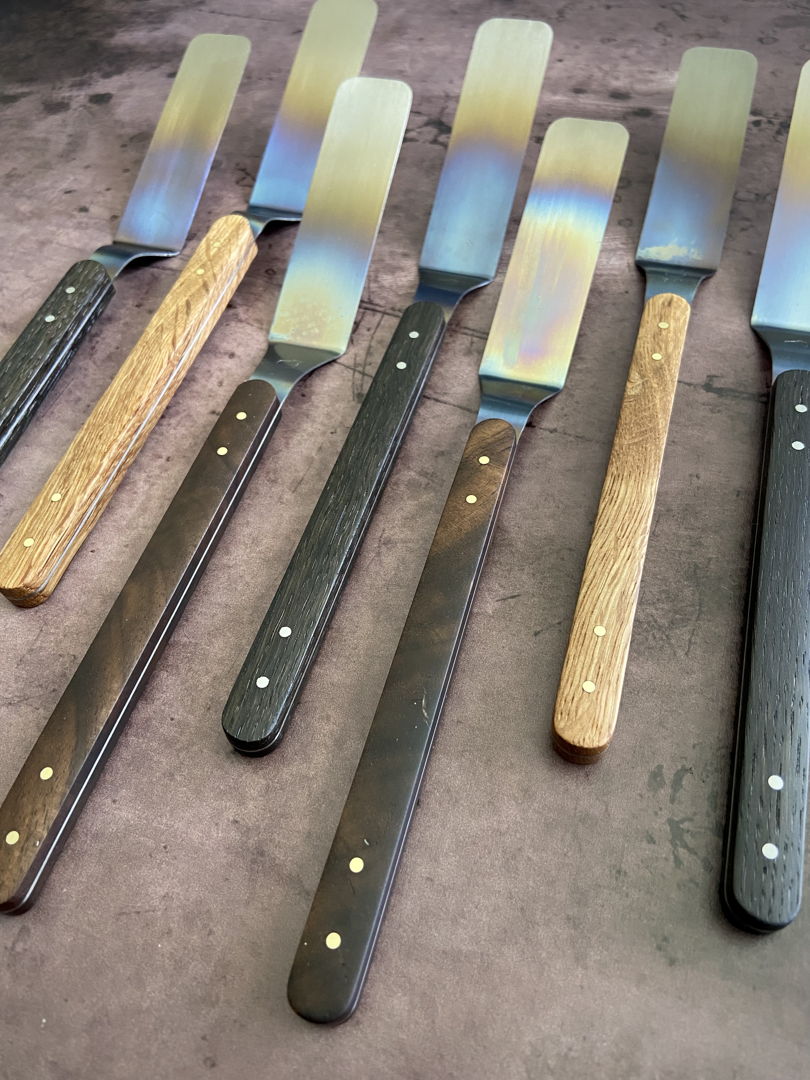 Titanium offset spatula with a variety of wood scales and brass or stainless pins.