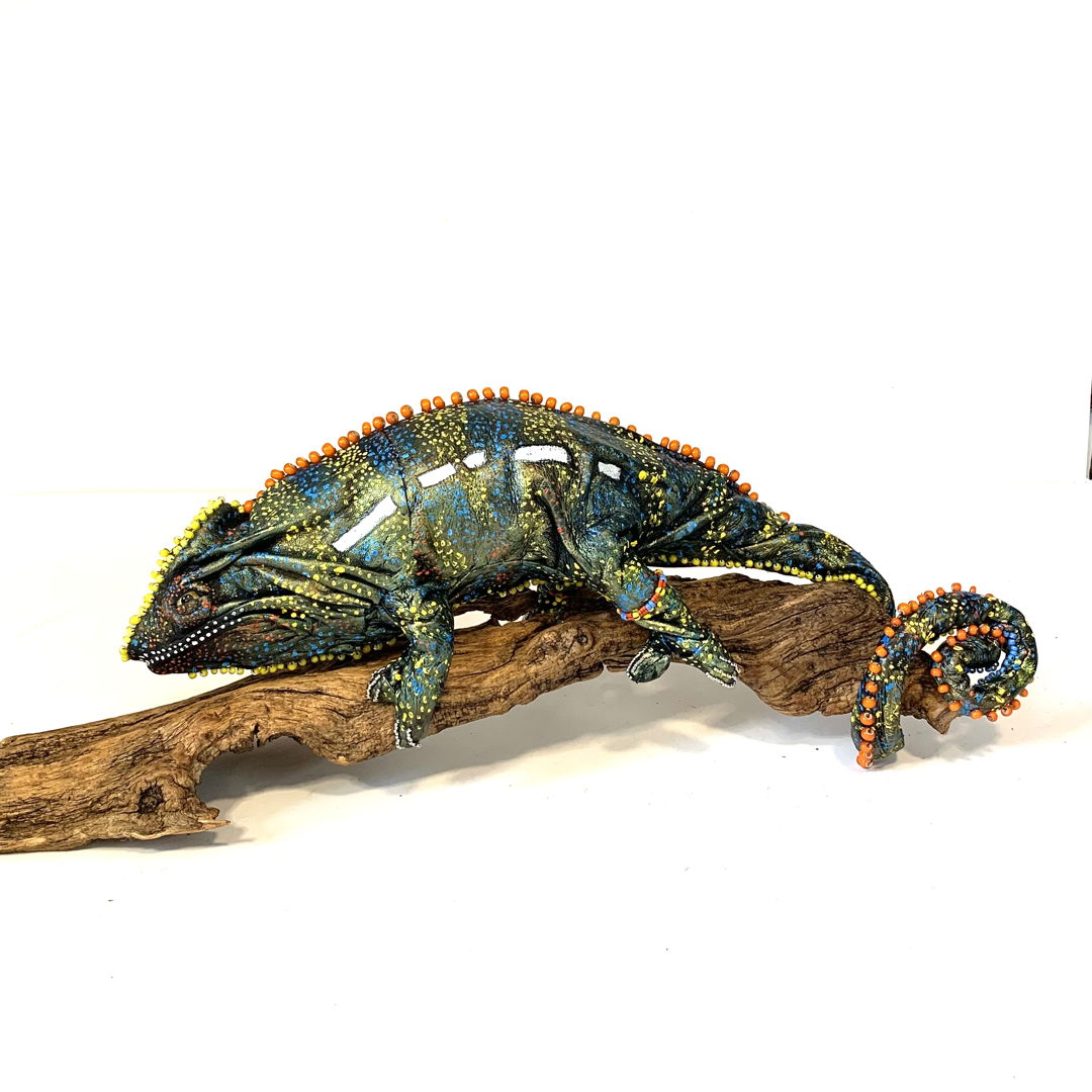 Leather and bead creature inspired by Panther Chameleons on a wood sculpture. Wire armature  glass eyes  black leather with added patina  and meticulous dot painting.