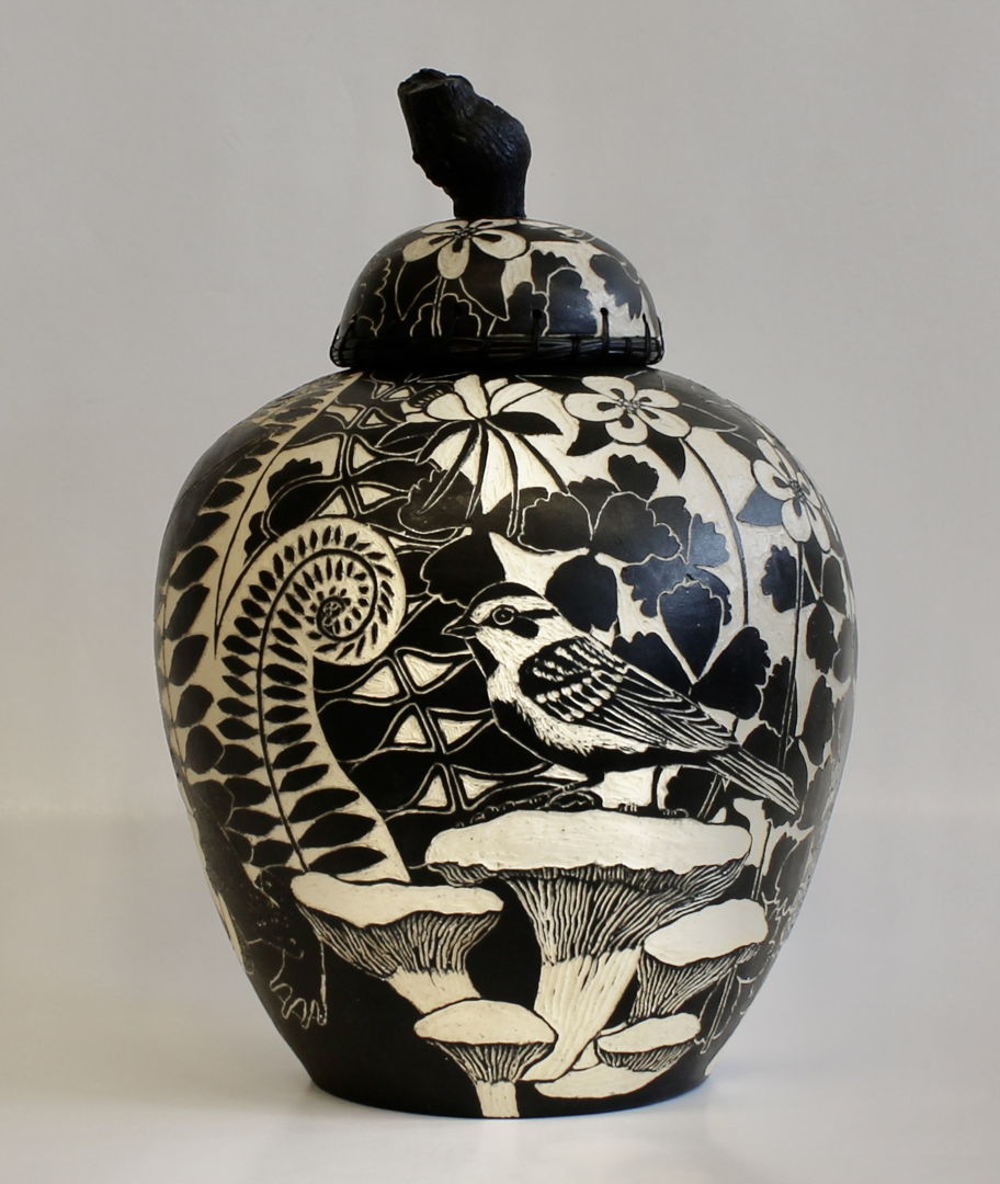 The lid of this jar is edged with woven pine needles and has a stained grapevine wood handle. The images on the surface of the pot were created using sgraffito and depict flowers  insects  birds and ferns.