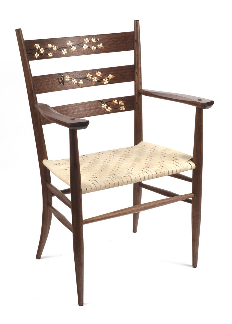 Walnut ladderback arm chair with dogwood marquetry on the back slats. The veneer marquetry is all cut  shaded and assembled by hand. The rear legs are steam bent and the seat is hand-woven reed in a herringbone pattern.