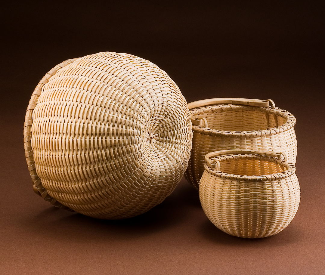 Nest of three swing handle baskets 6" dia. to 3" dia. Handcrafted using the tools and techniques of the Maine woodsmen  Shakers  and Native American basketmakers. Woven of pounded and hand-scraped brown ash splint with hand split  carved  and green bent.