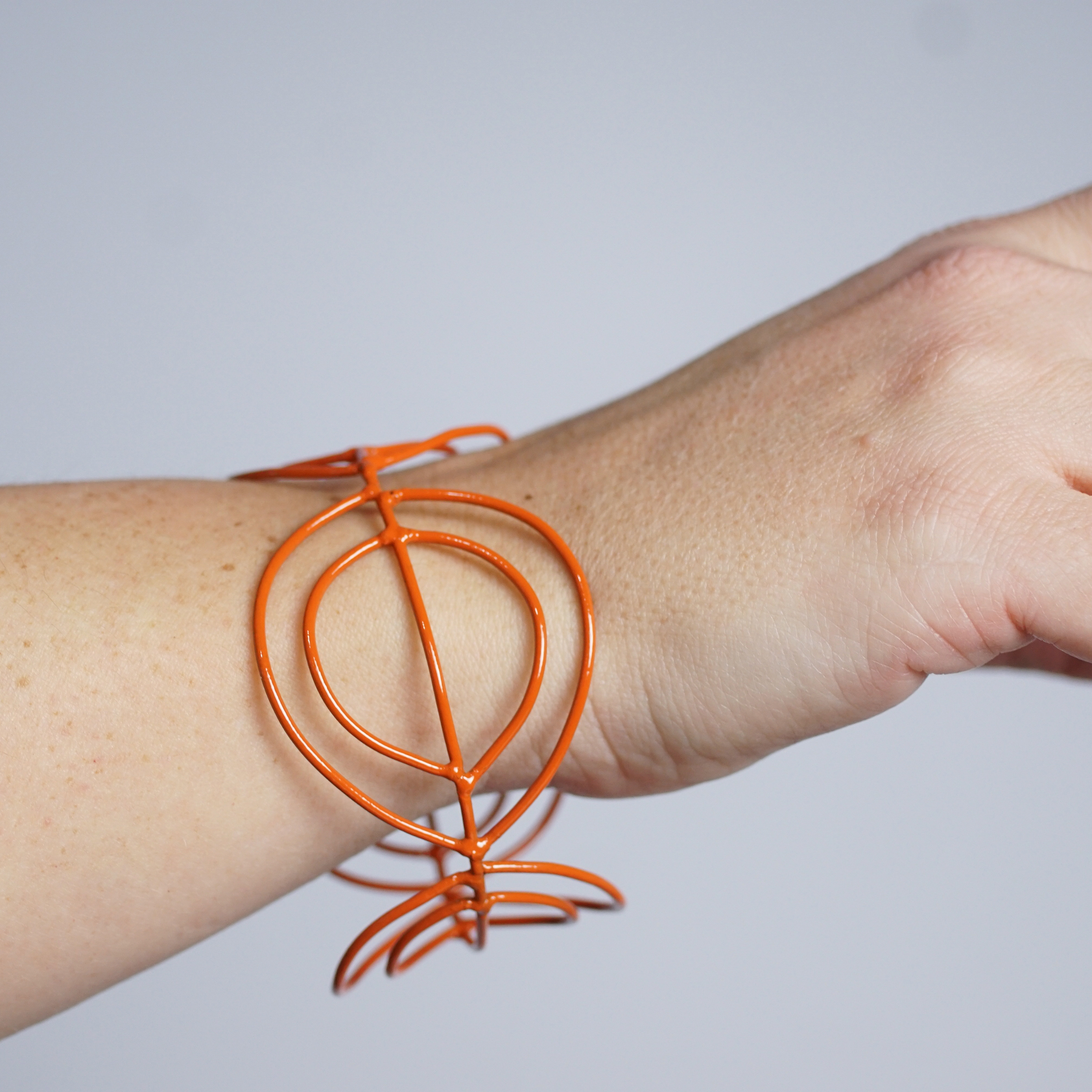 cuff bracelet with orange wire shapes with a lot of negative space
