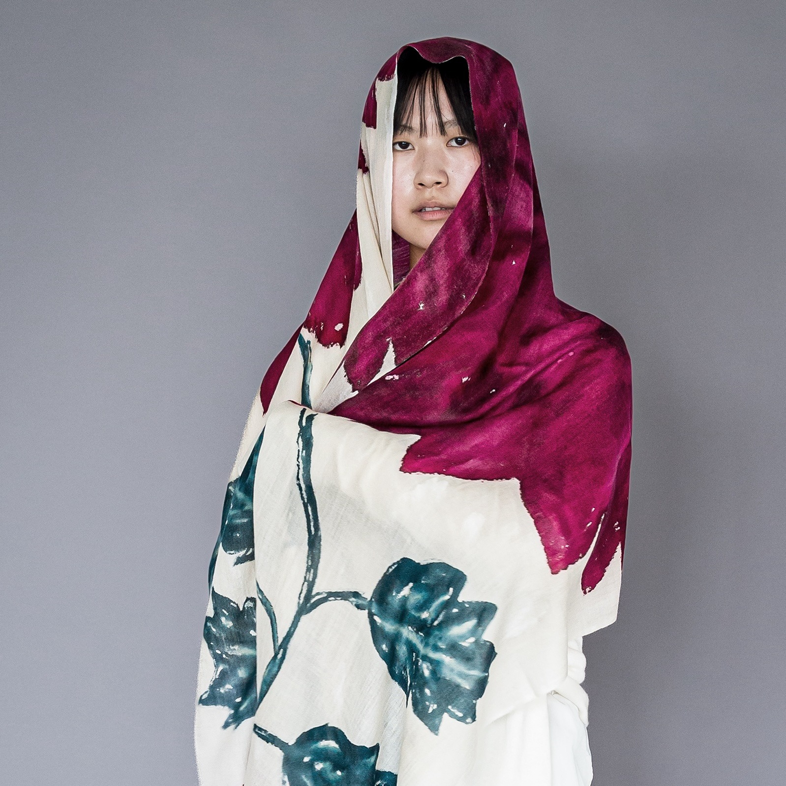 Model draped in large shawl with magenta flower and leaves