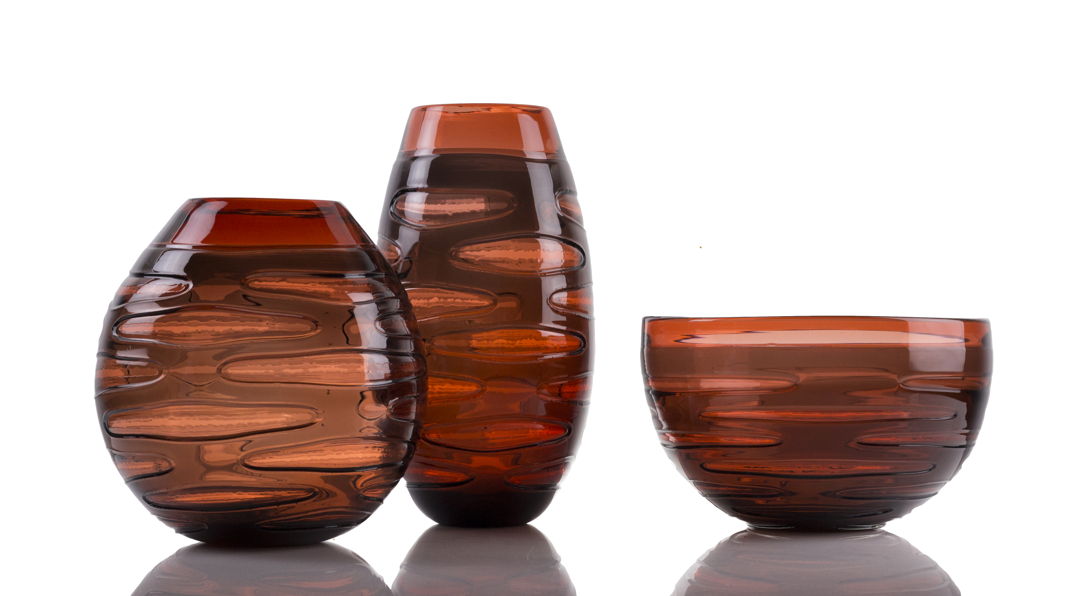 The INCISION SERIES of bottles + vases are created using a “stuffed cup” technique. A cup is blown  cooled  cut  brought back up to temperature and reformed into each shape we offer. Offered in translucent monochromatic color ways to emphasize the unique torn texture.