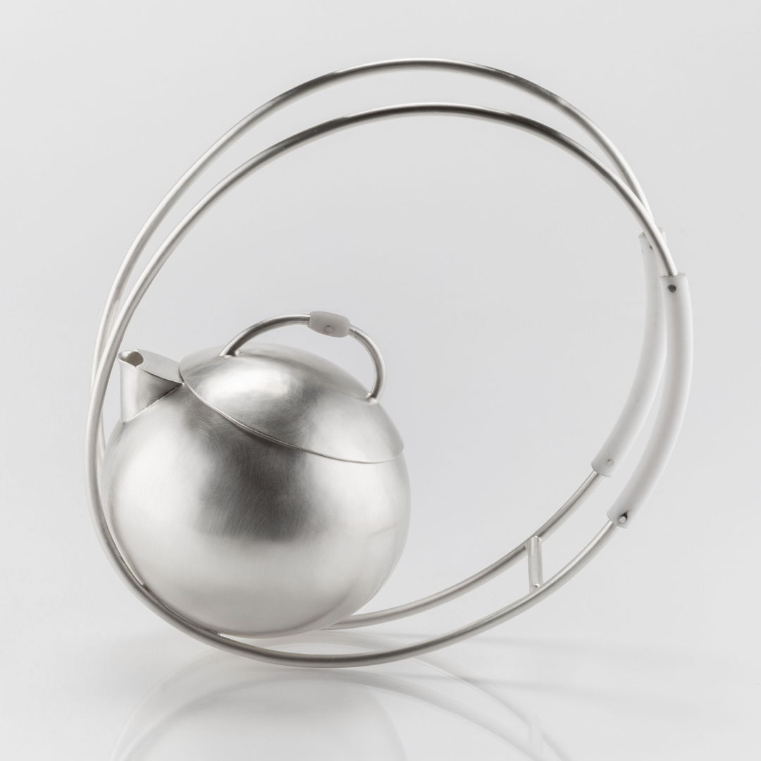 A fully functional sterling silver teapot. The piece rocks back and forth on the elliptical handles when put into motion. Techniques used in make this piece include hammering (raising  planishing  bouging)  soldering  filing  sanding  and riveting. Teflon and Delrin were to used as heat syncs.