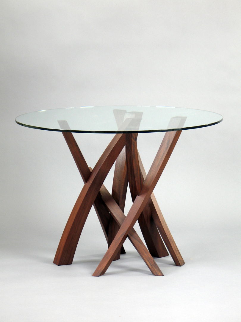 Round glass top  The base is made of walnut consisting of seven tapering arcs of varying size which intersect to form the dynamic structure.