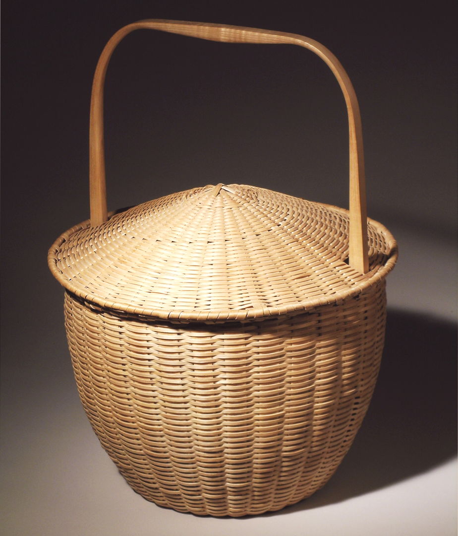 Captured lid basket. Handcrafted using the tools and techniques of the Maine woodsmen  Shakers  and Native American basketmakers. Woven of pounded brown ash splint with hand split  carved  and green bent brown ash rims and handles.