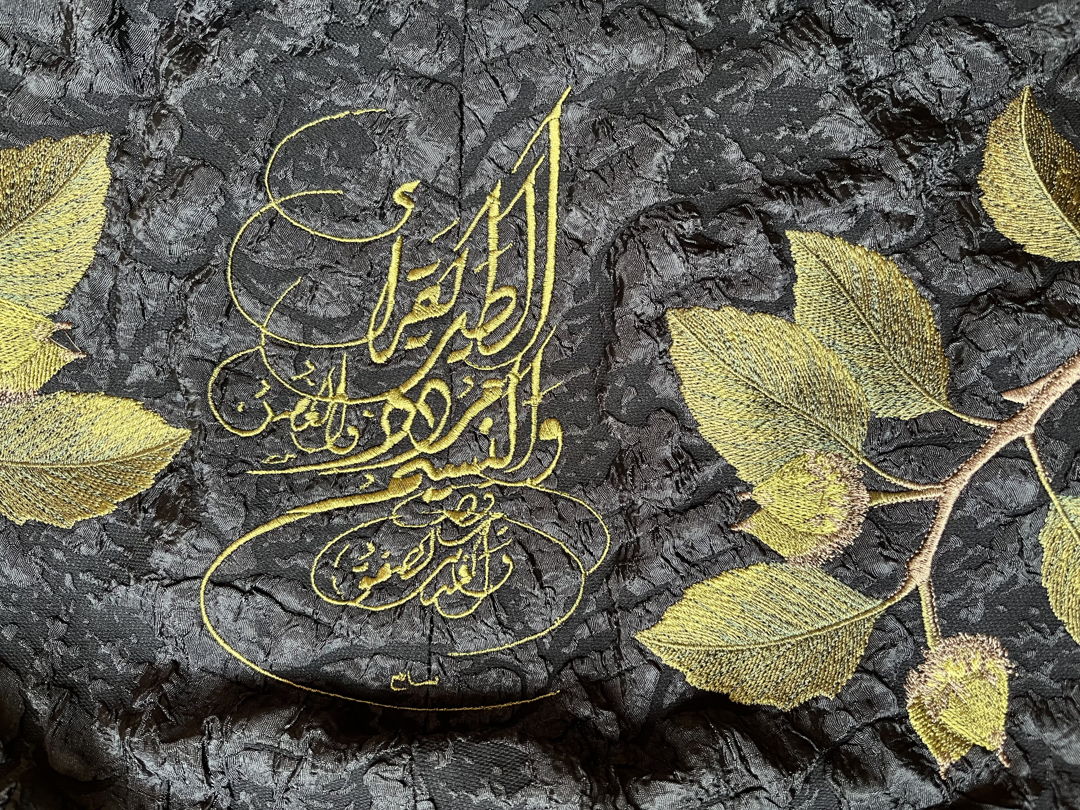 Detail of back collar of Bird Reads cocoon coat. Cocoon coat constructed using mill end and vintage fabrics. Custom embroidery and poem by Ibn al-Saygh (14th century) written in English and Arabic calligraphy: "The bird reads  the breeze echos  the branch dances  and the brook applauds."