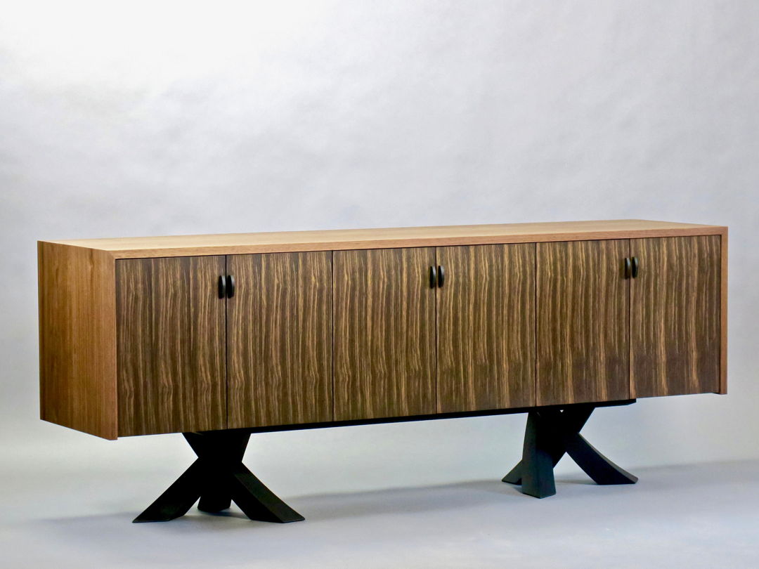 Sculptural ebonized walnut legs of intersecting tapered arcs support a case made of solid walnut featuring 3000 year old rift sawn bog oak doors and pulls.