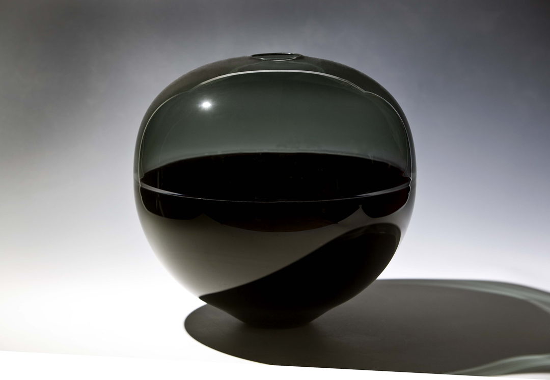 Tone on tone incalmo sphere with a dense black bottom and a transparent gray top.