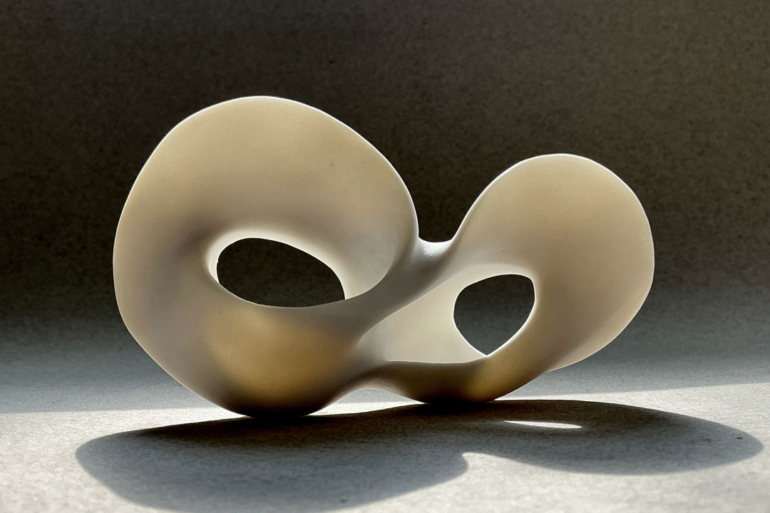 This high fired porcelain piece was created by pinching  carving  and handbuilding. It has an unglazed surface.