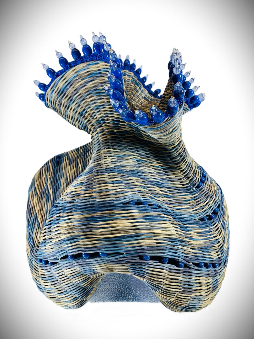 Hand-built pottery base woven with dyed reed and embellished with glass beads and a leather rim.