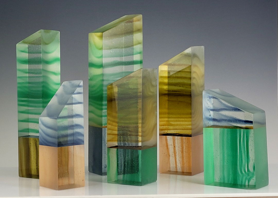 Six cast and cold-worked glass creations. These started out as 4 blocks created in a kiln  then sawed into multiple pieces. Colored epoxy joined two of these smaller pieces together. Grinding and polishing completed each piece. Underlighting is included.