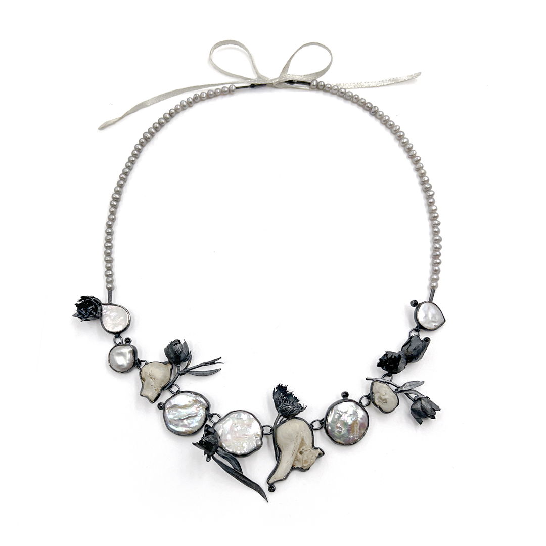 Bullae bones  baroque pearls  black diamonds  grey pearls  silver  satin. Cast marigolds. Cast and fabricated.