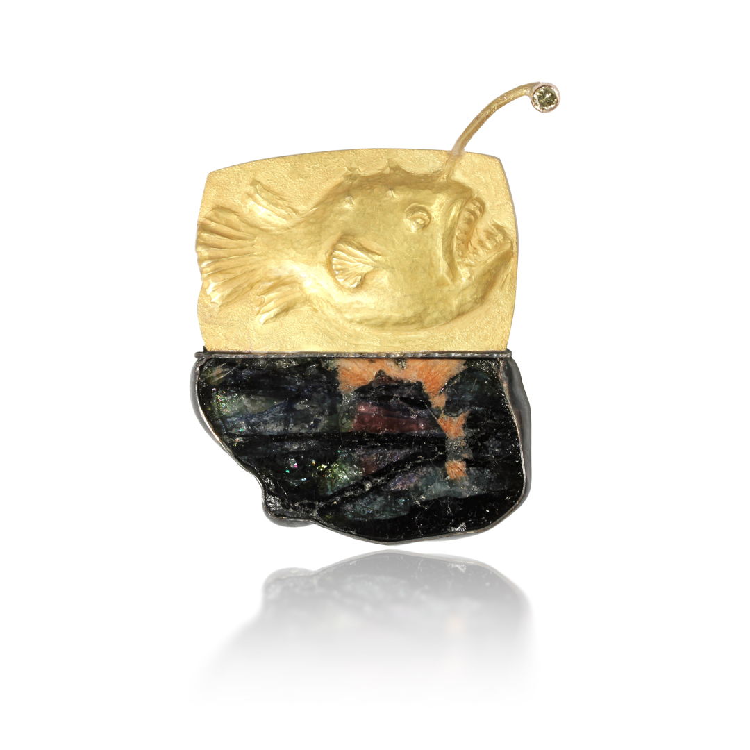 The angler fish is a gold repousse brooch /pendant. It has a diamond to represent it's light. this wonderful composite tourmaline crystal slice represents the deep water where it lives. The crystal is set in silver.