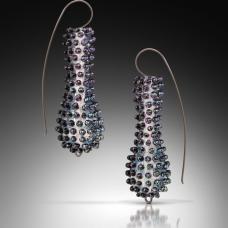 Torch-formed dichroic glass  soda lime glass  oxidized sterling silver. The core shapes are made first using a graphite dowel &amp;amp; gravity. The first basic shape goes into the kiln while I start the second. Once I match the two earring shapes  I add the outer texture in iridescent black dichroic glass.