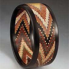 This bracelet has 12 different specie of wood in it all natural colors and artist dyed maple veneer. There are 600 pieces of wood in it with Ebony edges.