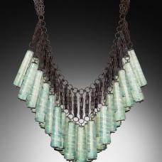 Each component is shaped in the flame using dichroic glass and a graphite paddle. The 30 glass components are then sewn onto hand-fabricated  oxidized sterling silver frame.