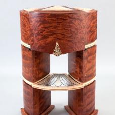 This complex fan-shaped piece  features three curved-sided irregular quadrilateral cabinets nested together and resting on a matching base. The exterior features waterfall bubinga  blistered big-leaf maple  copper-foiled art glass and mother of pearl inlays.The interior reveals patinated blue copper  mother of pearl and abalone inlays  a revolving carousel  pivoting drawers with pierced and carved bottoms and dividers  marquetry and art glass shelving.