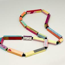 Pipage Necklace is composed of many rectangular-shaped pipes  each pipe a different length with different colors and patterns on each side and both ends. The little pipes are made from layered mat board. Colors and patterns are added using layers of papers “painted” on with brush and glue. The colorful pipes are linked with cord  with small black beads in between each one. The Pipage Necklace is sealed for wear  and comes as a single strand as seen here  as double strands  and earrings.