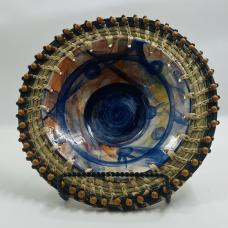 Wheel thrown vessel allowing the glazing process to create a majestic scape. Reclaimed glass is also fired in the piece that also offers balance as well. South Carolina coastal sweetgrass attached with wooden beads to bring framing and closure to the vessel.