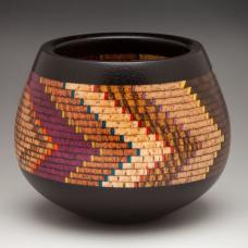 This small ceremonial bowl has 10 specie of wood and artist dyed maple veneer. there are 400 individual pieces of wood in it  with an Ebony base and rim. The shape of the bowl echoes the pattern of the lamination which reminds me of the Anasazi bowls