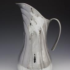 This large statement pitcher or ewer is hand raised from a single sheet of sterling silver. This swooping lines are chased in to big movement and grace to the form.