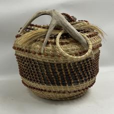 South Carolina sweet grass baskets with found deer antler which serves as an handle for the basket. Wooden beads are also used to highlight shape  form  and depth of the basket.
